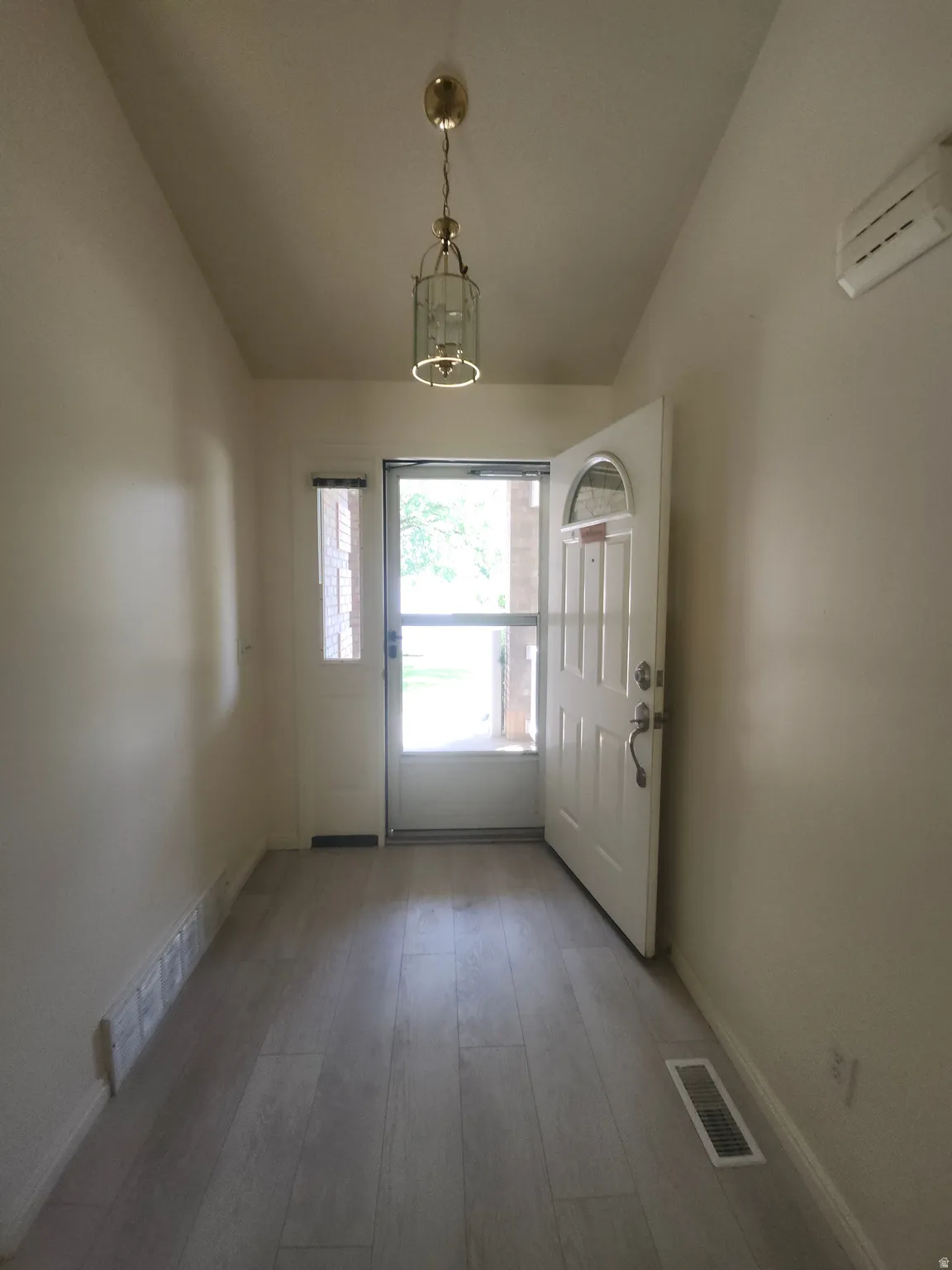 Entryway featuring wood-finish flooring, a white paneled entry door with an arched window, and a white side door with a rectangular window