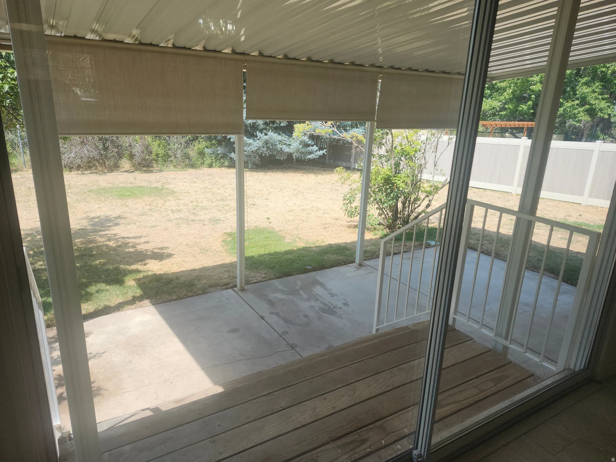 Covered patio featuring wood-finish decking, concrete slab, and metal railings