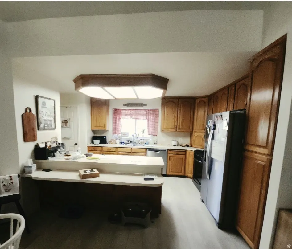 Kitchen featuring wood-finish cabinetry, light-toned countertops, and wood-finish flooring