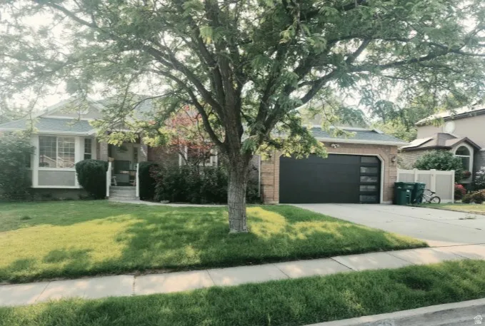 Single-story brick residence featuring a bay window, concrete driveway, and a modern garage door with multiple windows