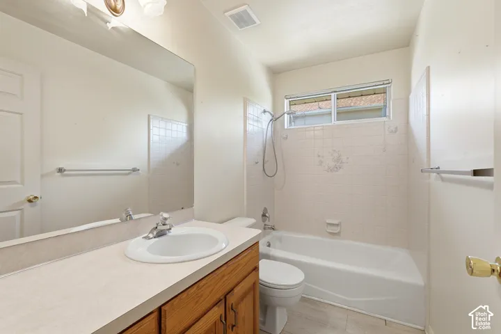 2nd Full Bathroom/Bathroom featuring a single-sink vanity with a solid-surface countertop, full-width wall mirror, wood-finish cabinetry, and a tub-shower combination with tile surround