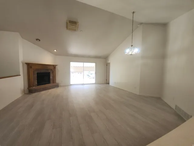 Living & Dining Room, Vaulted ceilings, brick fireplace with wood mantel, wood-finish flooring, recessed lighting, and sliding glass door
