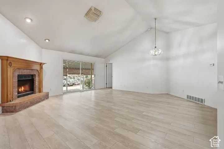 Vaulted ceiling with recessed lighting, wood-finish flooring, brick fireplace with a carved wood mantel, and sliding glass doors