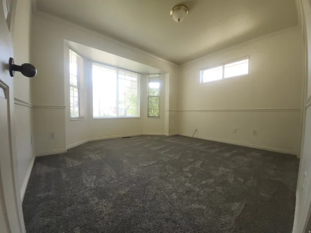 2nd Bedroom on main floor with bay window with multiple panes, ceiling-mounted light fixture, crown molding, chair rail molding, and grey carpet flooring