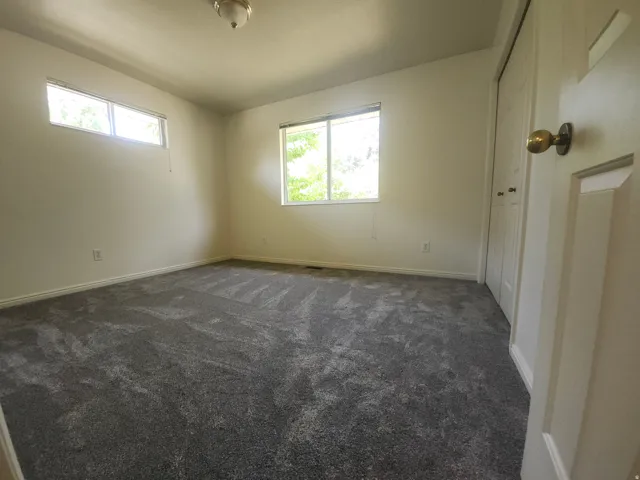 3rd Bedroom upstairs. Bright secondary bedroom featuring neutral wall finishes, dual windows with natural light, new carpeting in charcoal gray tones, and direct access to hallway entry