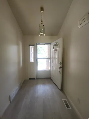 Entryway featuring wood-finish flooring, a white paneled entry door with an arched window, and a white side door with a rectangular window