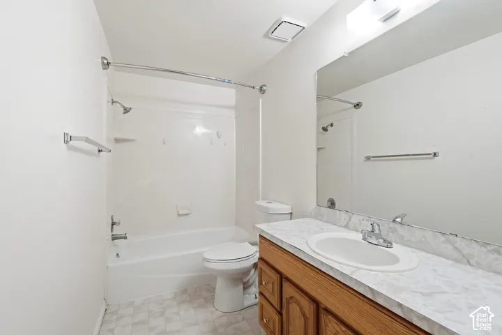 3rd full Bathroom featuring a wood-finish vanity with a stone-patterned countertop, an oval undermount sink, a large wall-mounted mirror, and a tub-shower combination with a surround