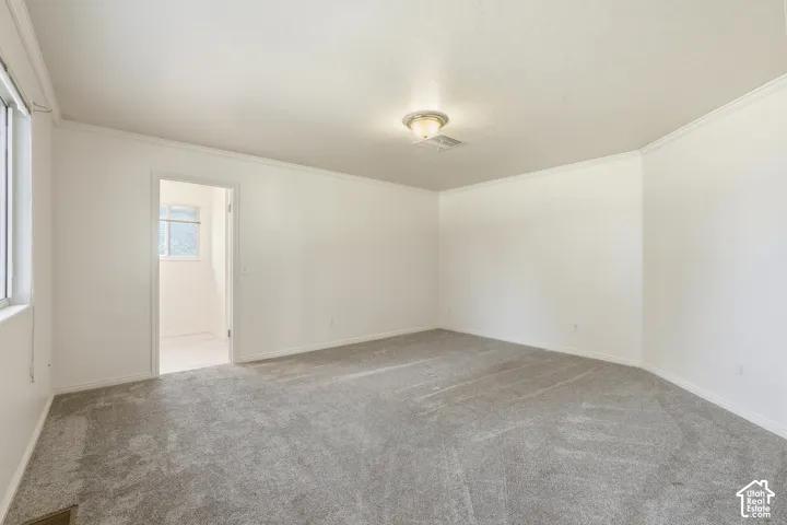 Primary Bedroom with on suite and huge walk in closet. Neutral-toned interior space featuring wall-to-wall carpeting, crown molding, and a central flush-mount ceiling fixture
