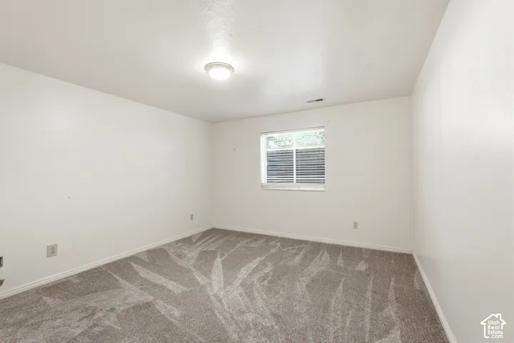 4th Bedroom BSMT/Room featuring neutral-toned carpeting, smooth-finish walls, a single-pane sliding window, and a central dome-style ceiling light fixture