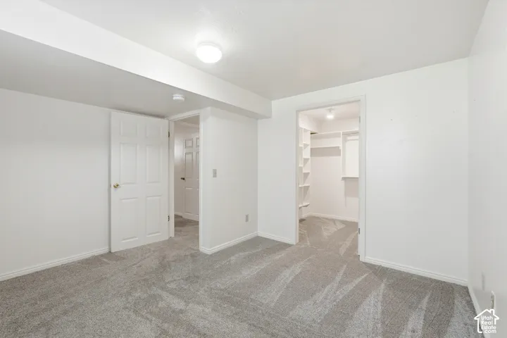 5th very large bedroom with walk in closet/ Neutral carpeted room featuring a walk-in closet with built-in shelving, two interior doors, and a ceiling-mounted light fixture