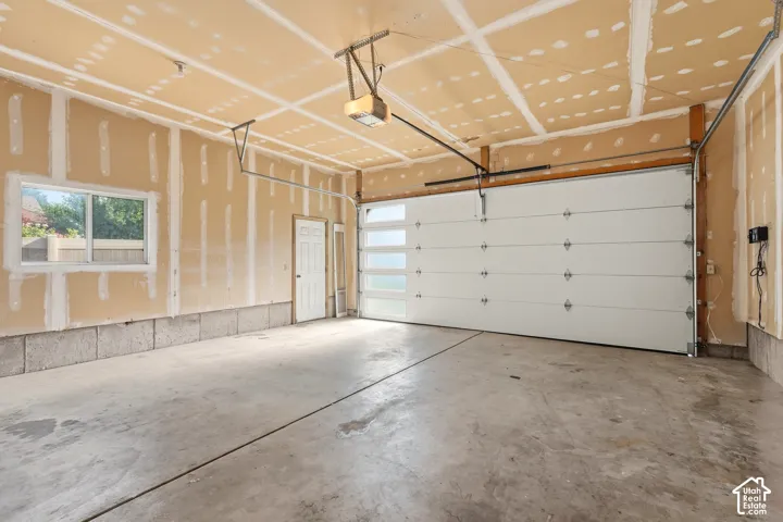 Enters into Kitchen/ Laundry room/ Attached two-car garage featuring a sectional door with frosted glass panels, concrete flooring, exterior-access door, and a sliding window