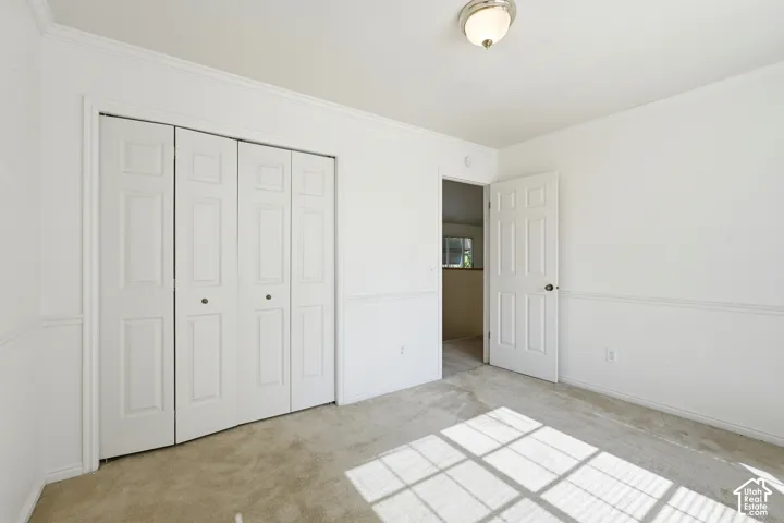 3rd  BedroomInterior space featuring neutral-toned carpeting, white wainscoting, four-panel bifold closet doors, and a six-panel interior door