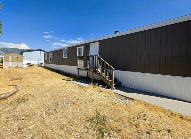 Gray exterior siding with white trim, featuring a wooden deck with stairs to the entrance