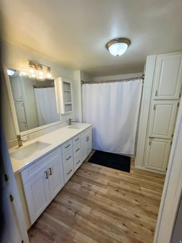 Primary Bathroom featuring a double vanity with white cabinetry, integrated sinks, and white quartz countertop.