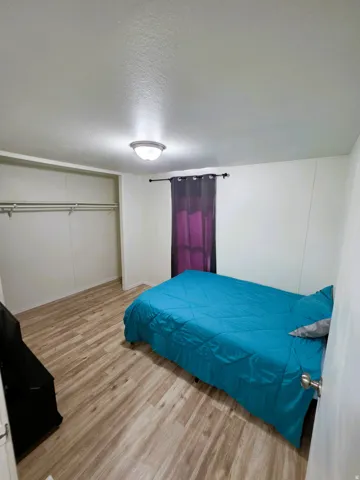 Second Bedroom featuring wood-finish flooring, a double-rod closet, white walls, and a ceiling-mounted light fixture