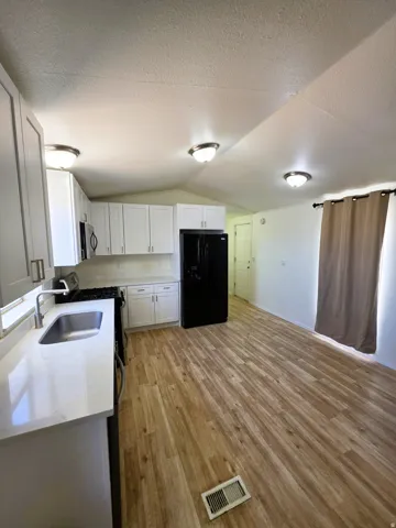Open-concept kitchen featuring white cabinetry, light-toned countertops, and wood-finish flooring