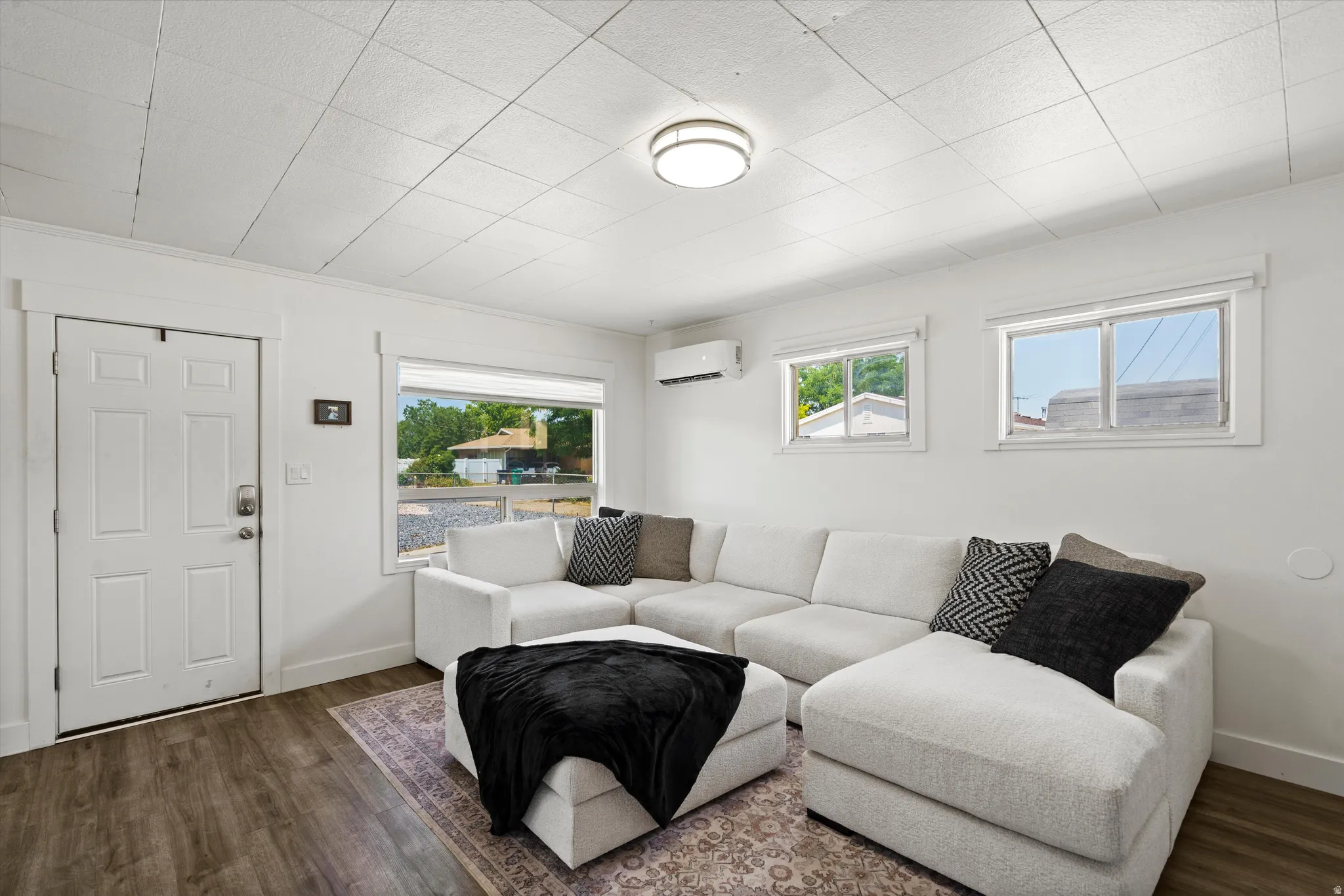 Bright room featuring wood-finish flooring, white walls, and a white paneled entry door