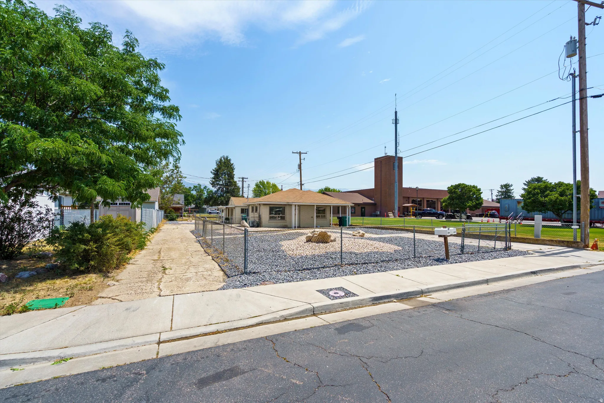 Ranch-style residence featuring a gravel front yard, chain-link fencing, and a concrete sidewalk