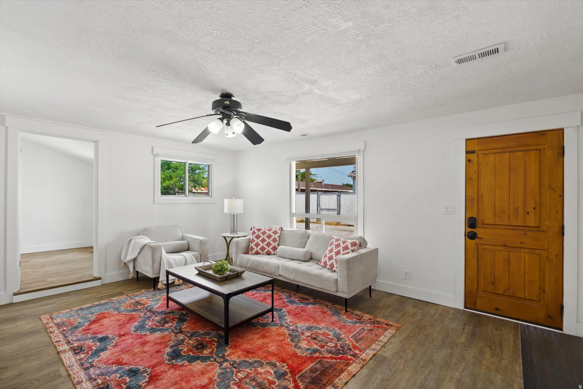 Bright living area featuring wood-finish flooring, white walls, and a ceiling fan