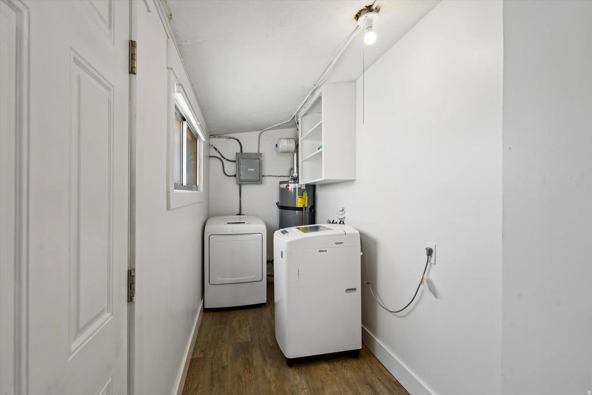Utility area featuring wood-finish flooring, white walls, and a window for natural light