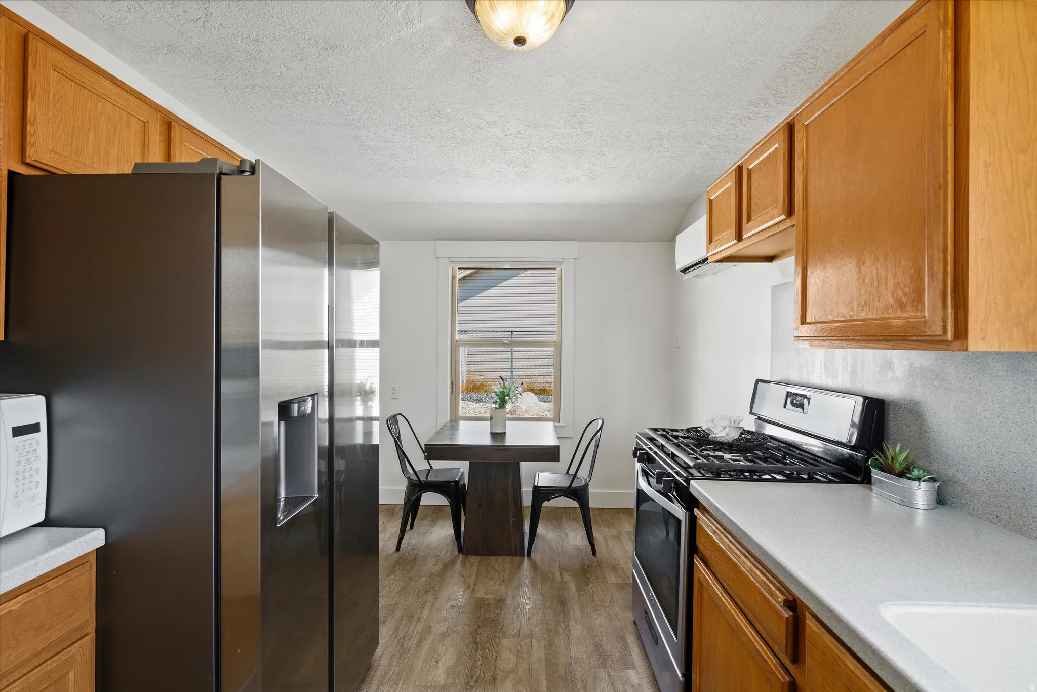 Galley kitchen featuring wood-finish cabinetry, light countertops, and wood-finish flooring