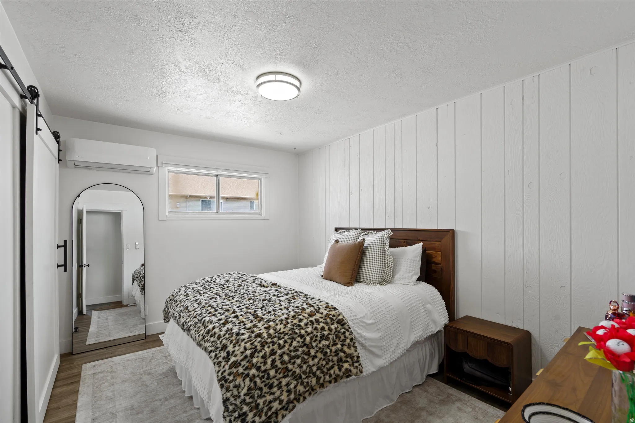 Bedroom featuring a white shiplap accent wall and wood-finish flooring