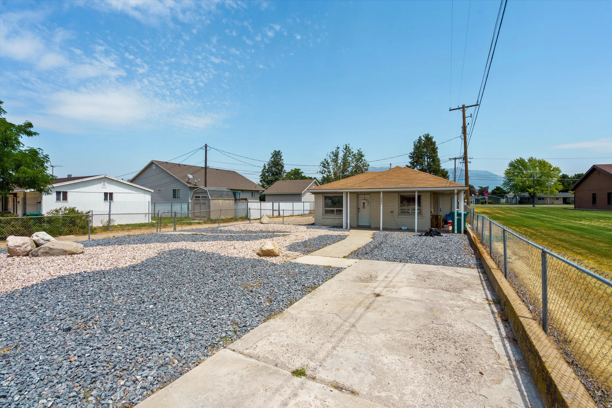 Single-story exterior with a covered porch entry, surrounded by a gravel landscape and a concrete driveway