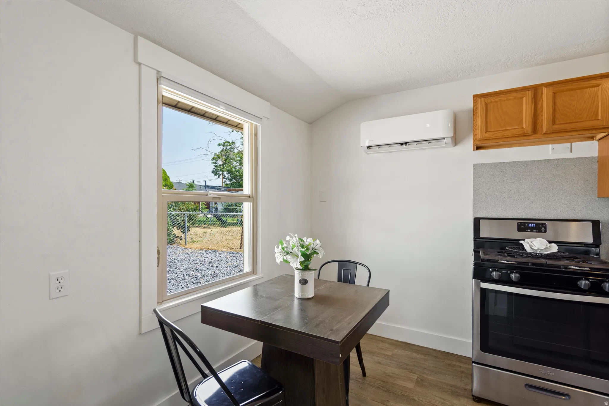 Kitchenette featuring a stainless steel gas range, wood-finish flooring, and a window with white trim