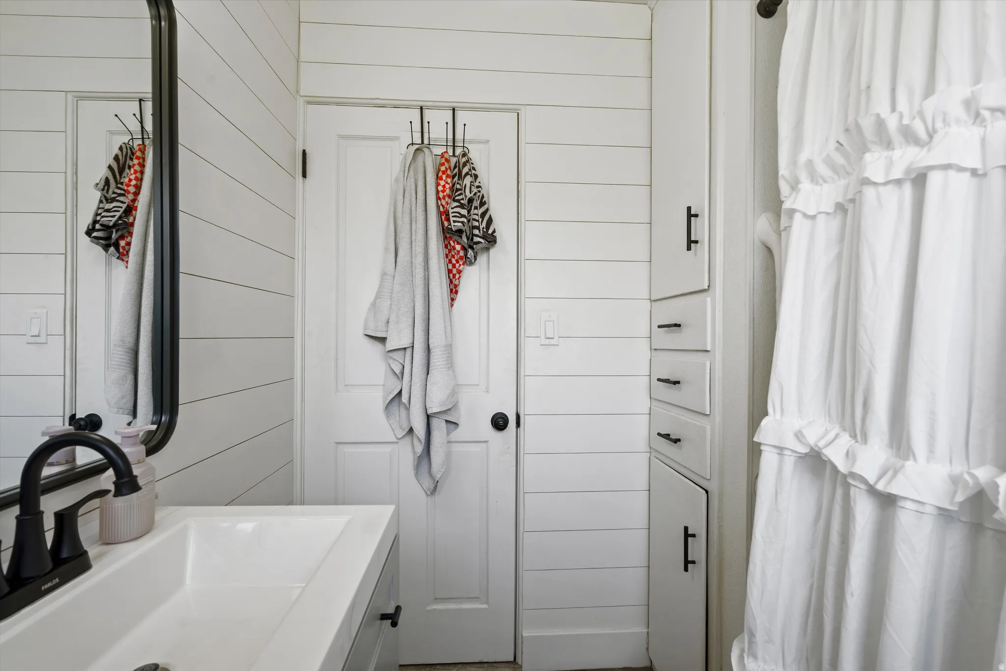 Bathroom featuring shiplap walls and built-in storage cabinetry