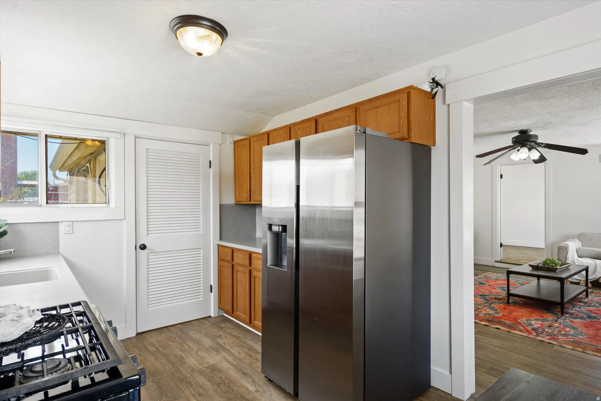Kitchen featuring stainless steel appliances, wood-finish flooring, light wood cabinetry, and a window for natural light