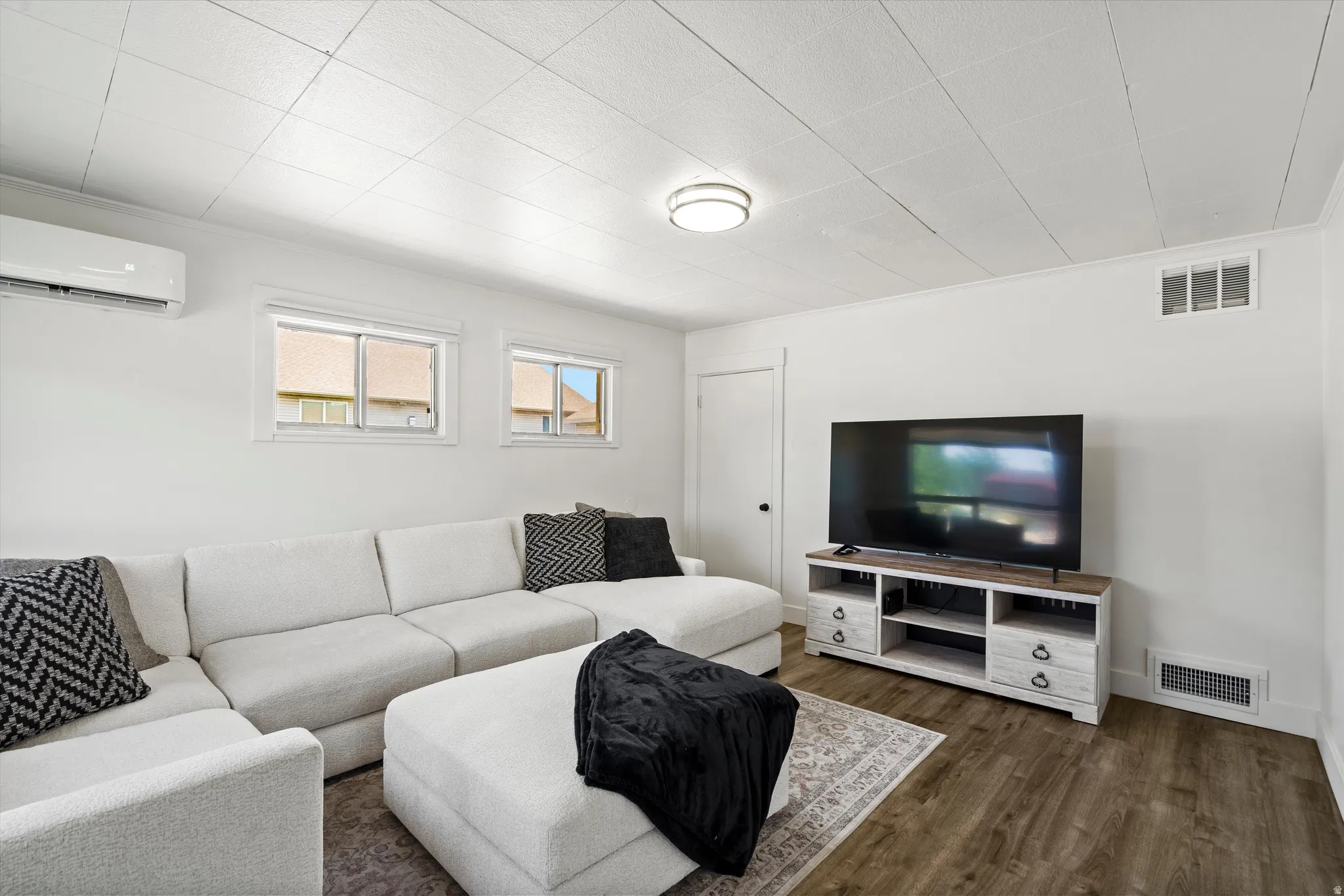 Living area featuring wood-finish flooring, crisp white walls, and a recessed panel ceiling
