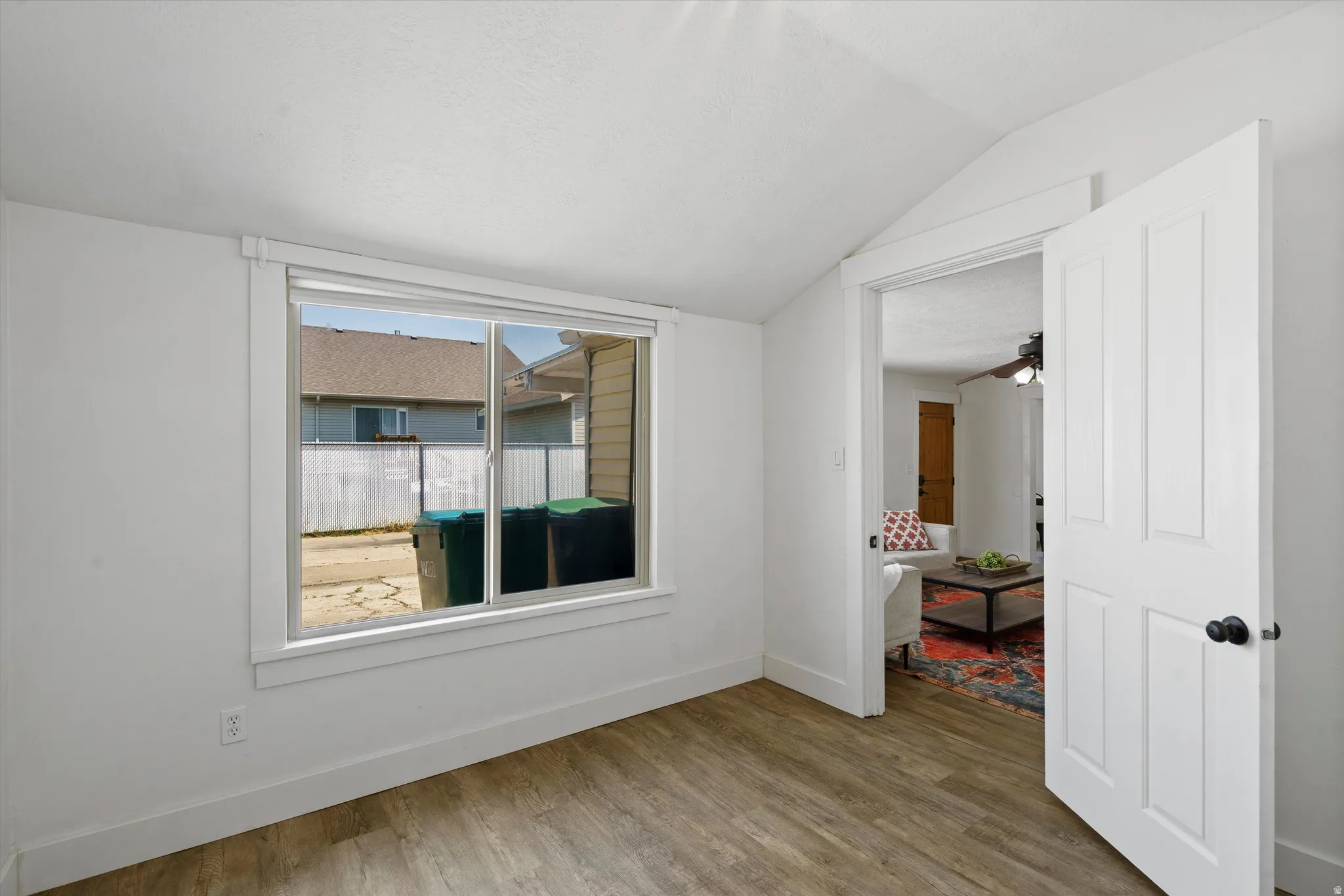 Room featuring wood-finish flooring, a white paneled door with matte black hardware, and a window with white trim