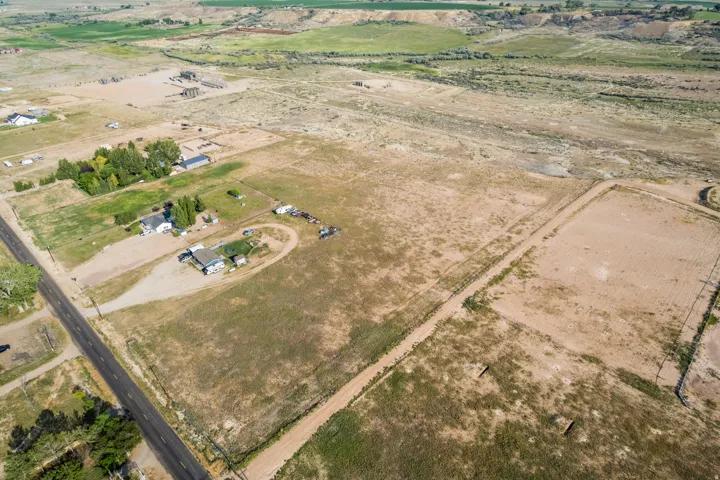 Expansive rural property featuring multiple structures, a paved road frontage, and substantial undeveloped land