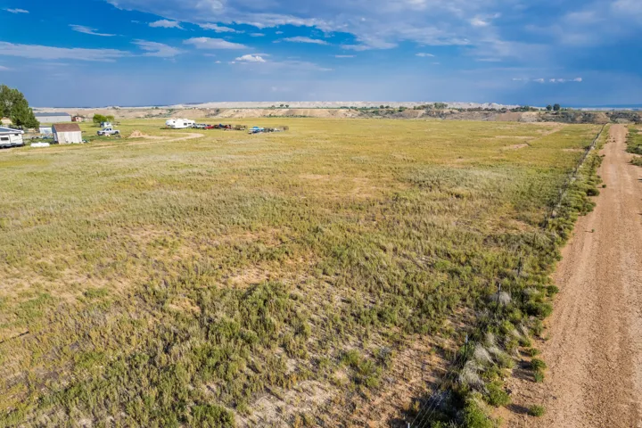 Expansive undeveloped land featuring natural vegetation and a visible dirt road along the property line