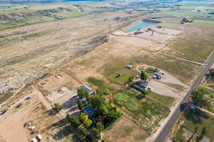 Expansive rural property featuring multiple structures, mature trees, and open land