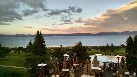 Expansive outdoor deck with multiple dining areas and lake scenery