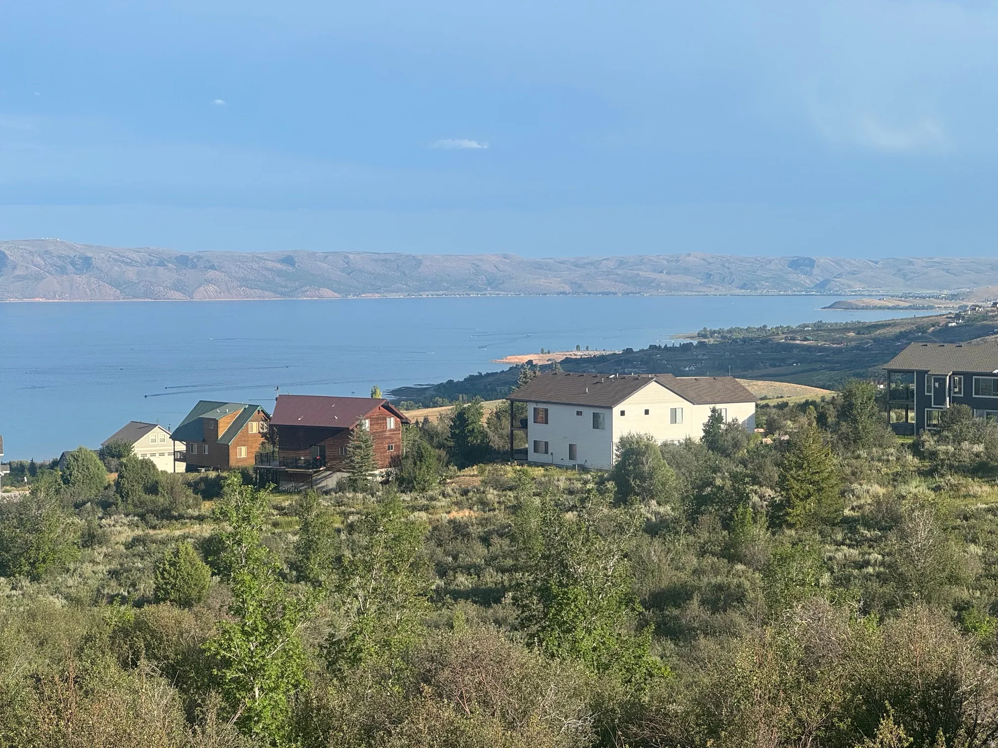 Expansive lake and mountain scenery with multiple residences situated on a hillside