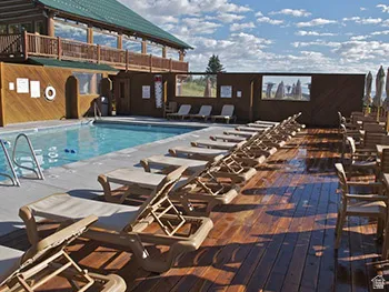 Outdoor swimming pool with a concrete surround, wood-finish decking, and a multi-level building with a green roof