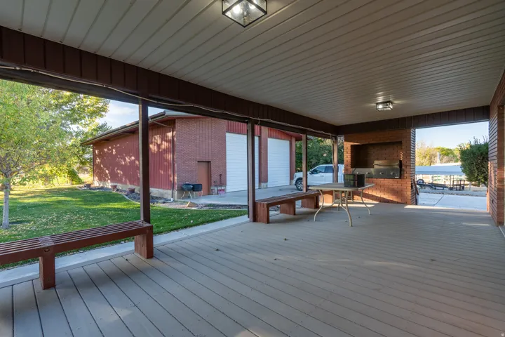 Spacious covered patio with wood-finish flooring and a built-in brick grilling area