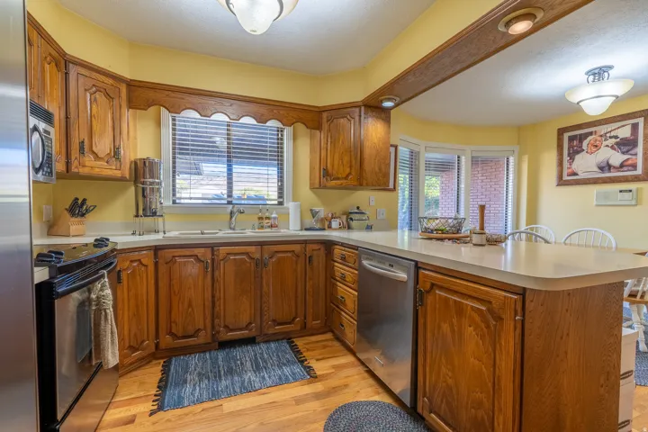 Kitchen featuring wood-finish cabinetry, light-toned countertops, and wood-finish flooring
