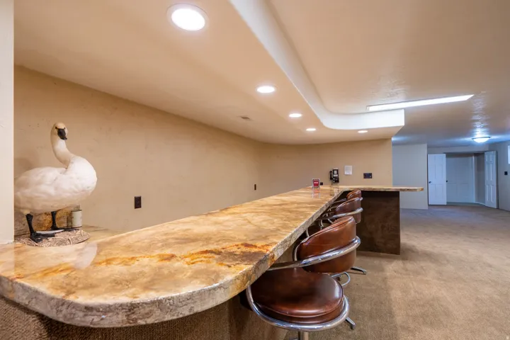 Curved bar with a patterned countertop, recessed lighting, and integrated bar seating
