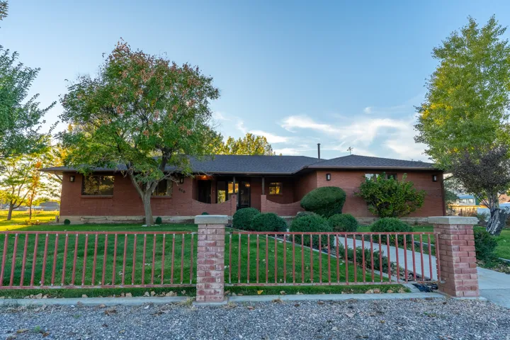 Brick ranch-style residence featuring a dark shingled roof and curved architectural elements