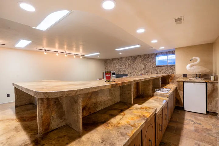 Expansive bar area featuring a stone-look countertop with integrated sink, built-in cabinetry, and a compact refrigerator