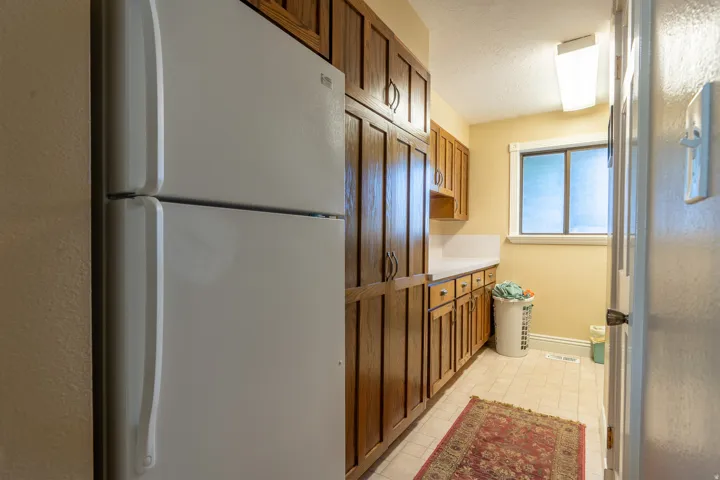 Kitchenette or utility space with extensive wood cabinetry, white countertops, and tile flooring
