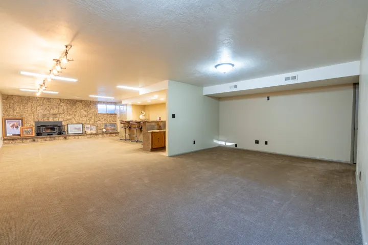 Expansive lower-level room featuring a full-height stone accent wall with an integrated fireplace and hearth