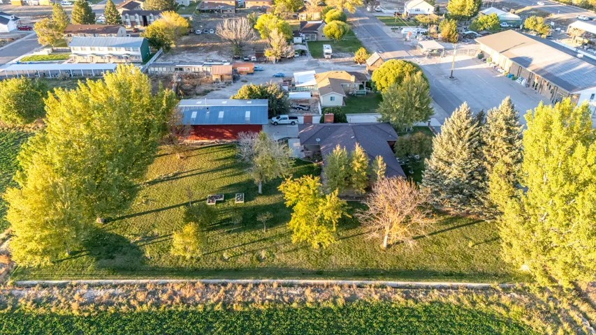 Spacious property featuring a large primary residence with a dark shingle roof, a red barn-style auxiliary building with a metal roof, and an expansive grassy yard