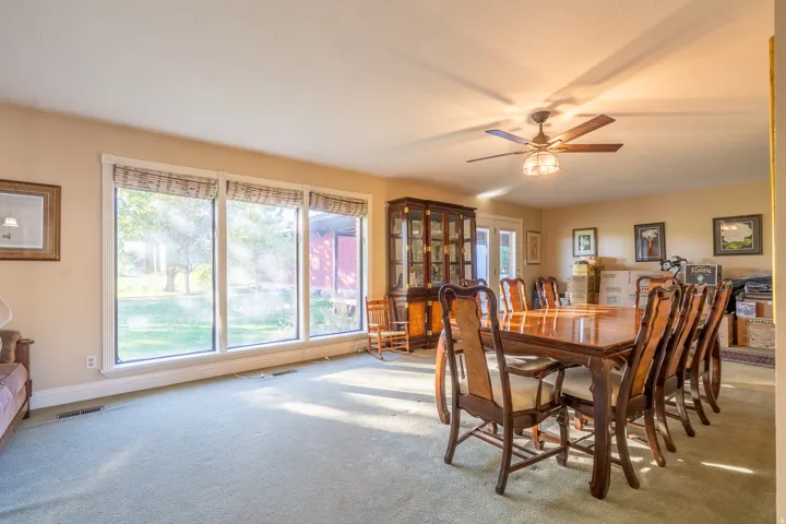 Spacious room featuring a wall of three large windows, light tan wall paint, and green carpet flooring