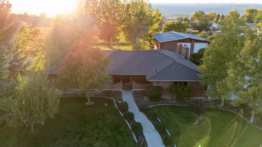 Expansive property featuring a single-story residence with a dark shingle roof, brick exterior, and multiple chimneys
