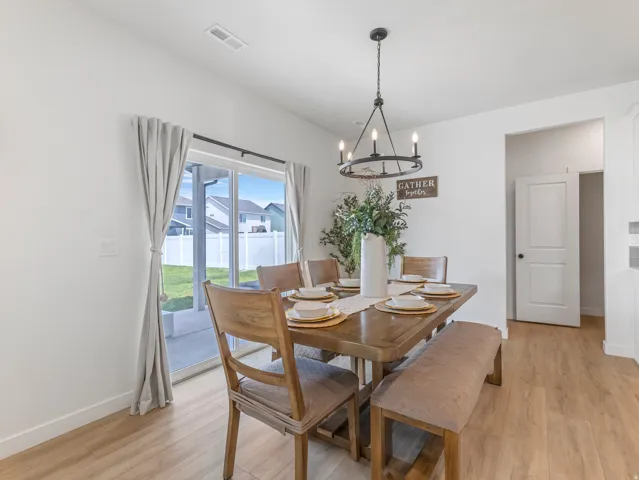 Spacious dining area featuring wood-finish flooring and a contemporary chandelier