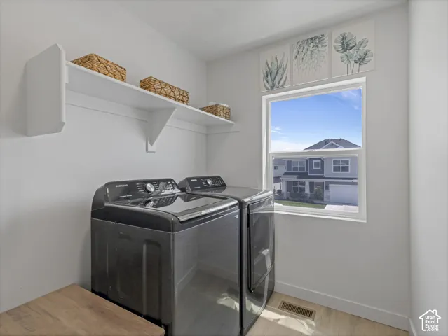 Dedicated laundry area featuring a window, overhead shelving, and wood-finish flooring